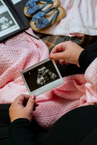 A pregnant woman lies on an exam table as a healthcare worker performs an ultrasound scan.