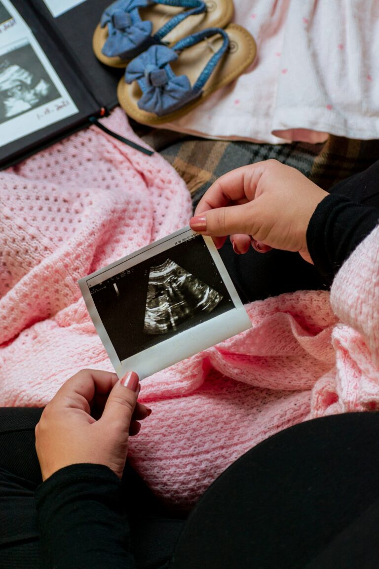 A pregnant woman lies on an exam table as a healthcare worker performs an ultrasound scan.